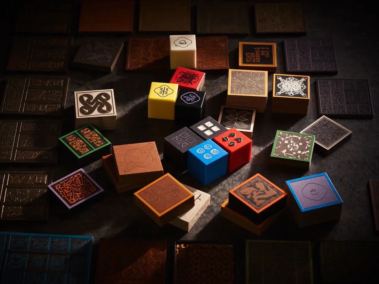 Strategiespiel von oben: Holzwürfel, Plättchen und Spielertableaus im Lichtkegel